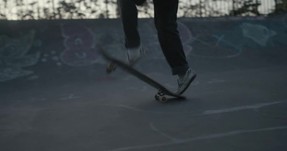 A skateboarder jumps into the air and flips their skateboard below them before successfully landing and continuing to skate