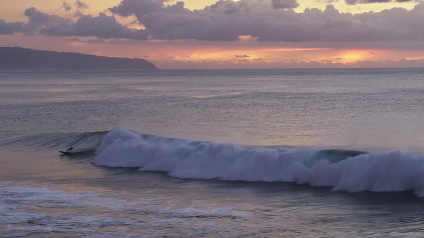 A surfer catches a wave in Hawaii at Sunset Beach