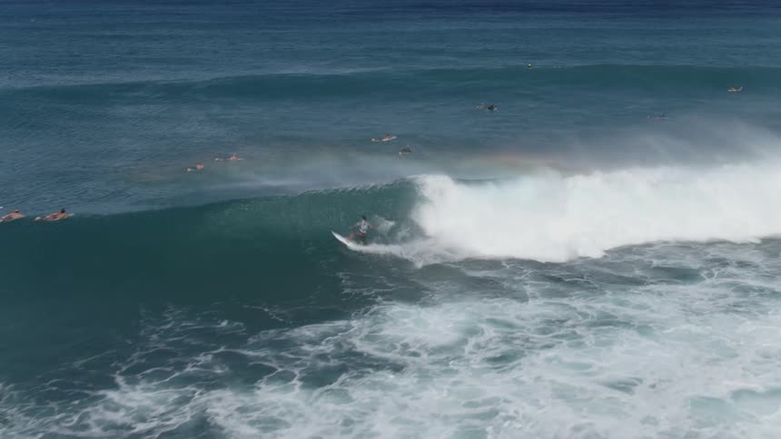 Many people in the water as a surfer rides a big wave and goes under water