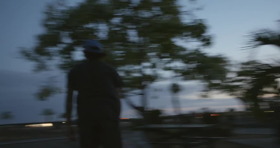 A man skating on a skateboard in a skate park with trees the sky and clouds in the background