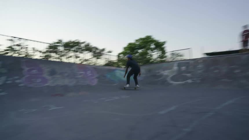 Young man riding a skateboard in a skating park at morning