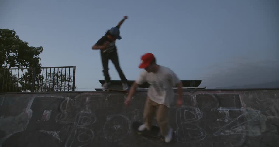 Two men skateboarding around each other