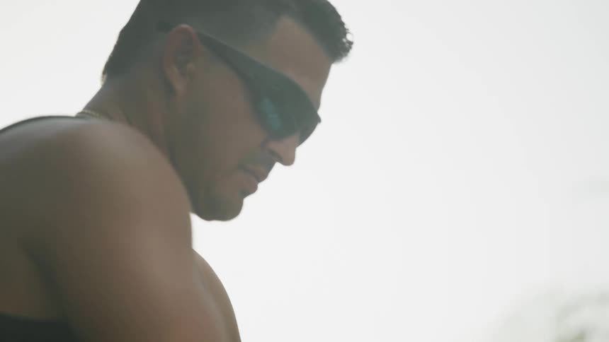 A man with sunglasses with trees the sky and clouds in the background