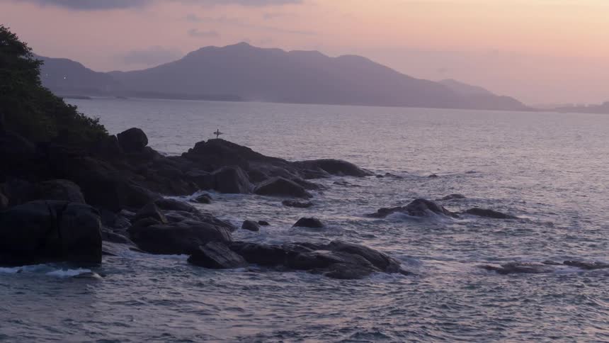 A small cross is on the rocks by the shore