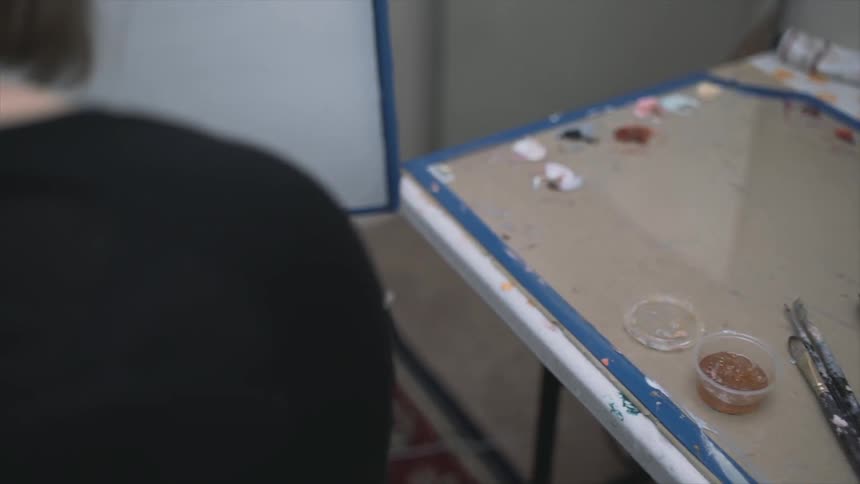 A woman picks up a paint brush