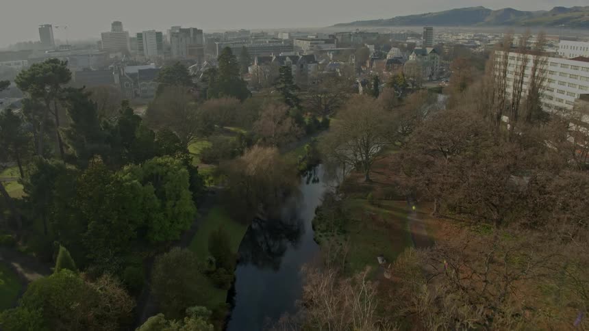 Aerial view of a river flowing through a park in the city at morning
