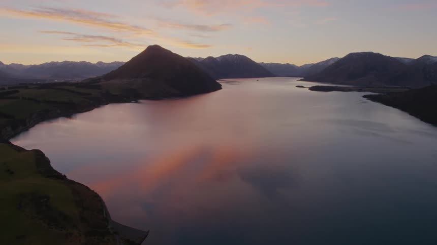 A lake with a mountain range the sky and clouds in the background