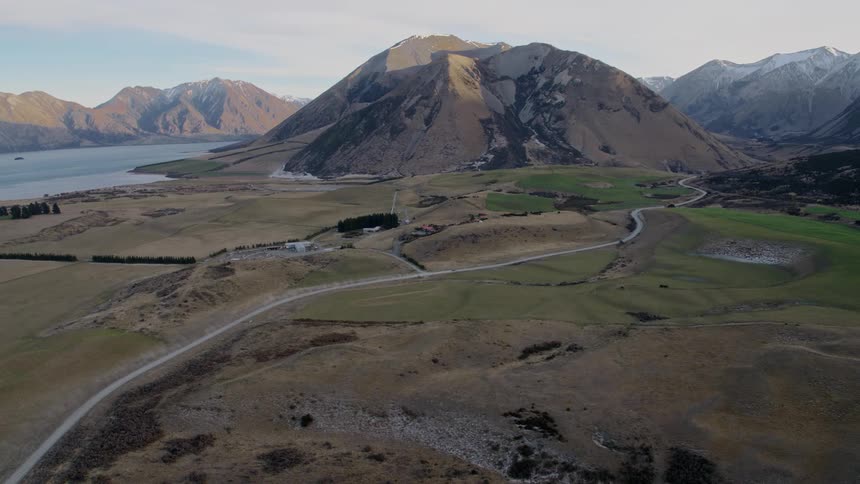 A road through a rolling countryside towards a mountain valley