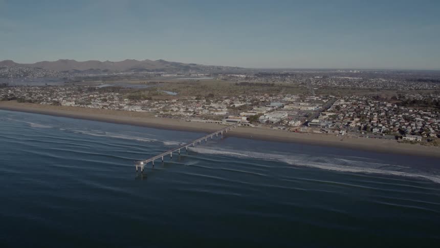 An aerial view of a coastal city and pier in the daytime