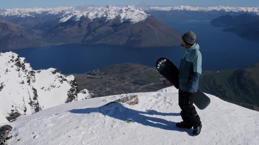 A snowboarder takes in the view from the top of a mountain
