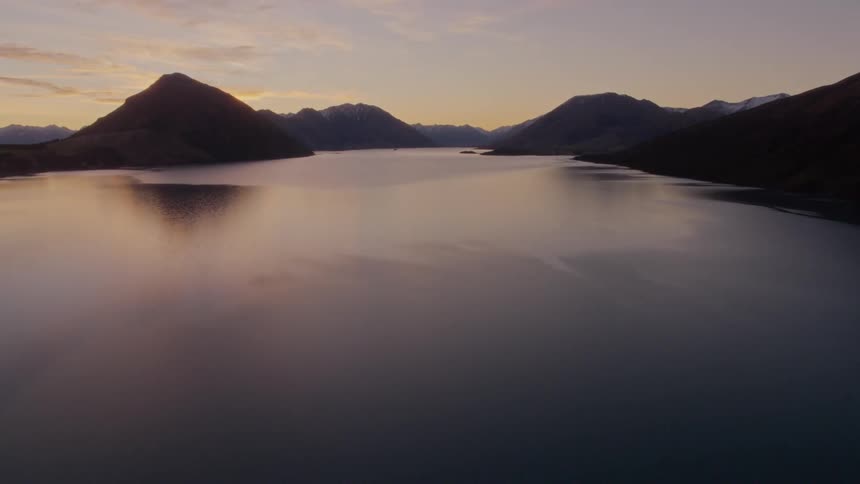 A wide river through a mountain valley at sunset
