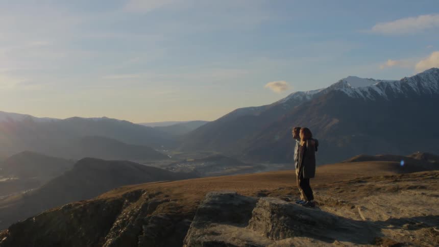 A couple walk to the edge of a cliff to take in the view