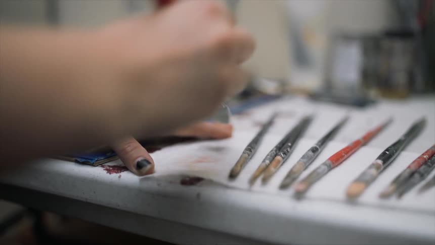 A person is cleaning a brush on paper
