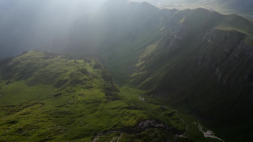 Grass covered hillside and mountains under a hazy sky