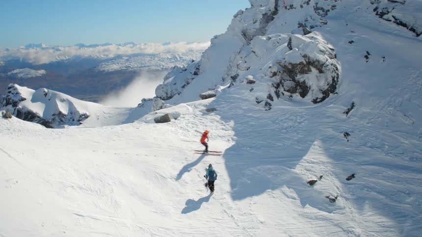 A skier is climbing the mountain as another skis by