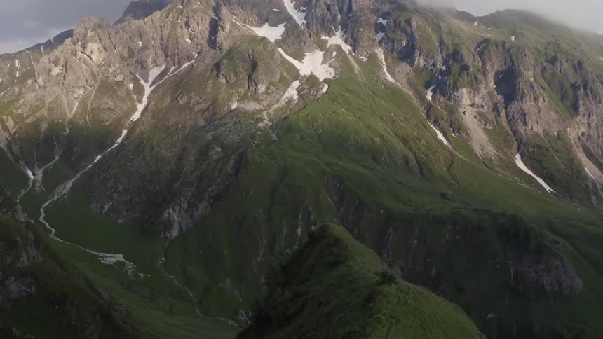 Aerial view of the tall mountain peak covered in clouds in the morning