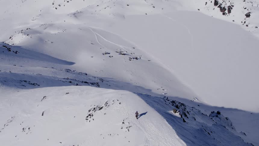 People on top of a snow covered mountain with several mountains nearby