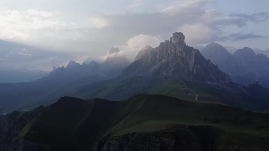 Aerial view of a road through the tall peaks of a mountain range at morning