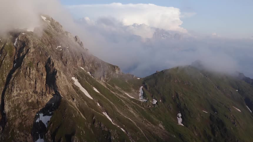 Thick clouds and fog roll over mountains early in the morning