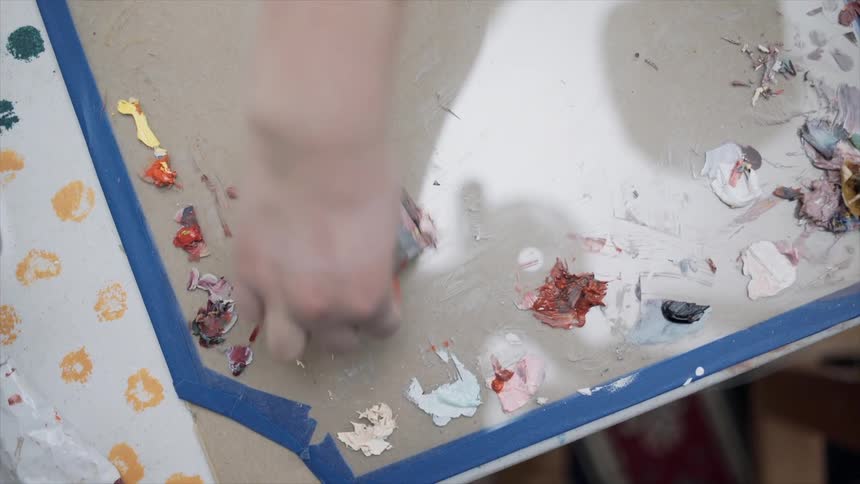 Person cleaning dried paint from a palette with a blade
