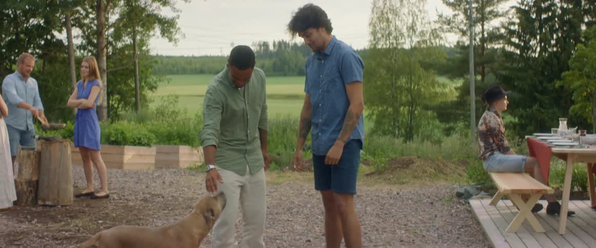 Two men high fiving and hugging while greeting each other at an outdoors get together