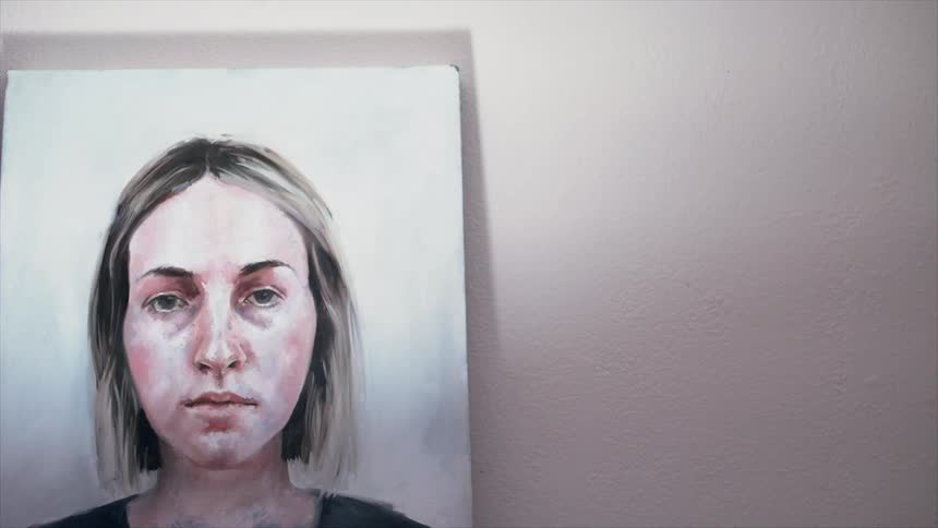 A portrait of a woman hangs on a wall