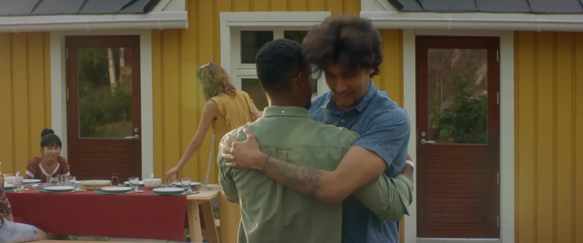 A man greets and hugs his friend as he arrives for an outdoor dinner party