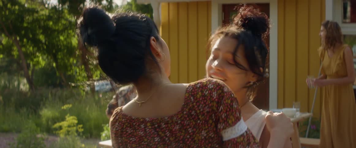 Two women hug happily standing outside a home