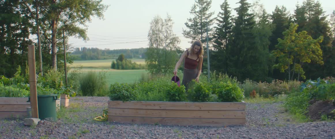 Woman waters plants in a raised garden bed