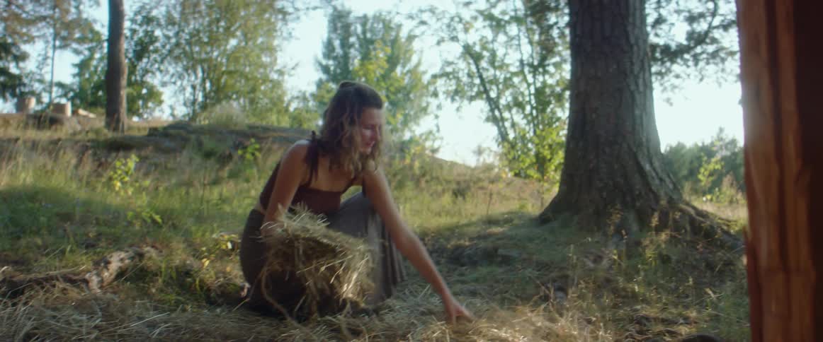 A woman spreads hay on the ground