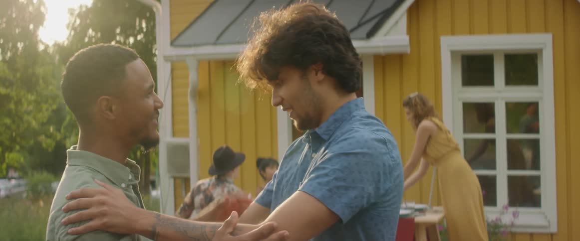 A man ruffles another mans hair in fun after greeting each other with a hug