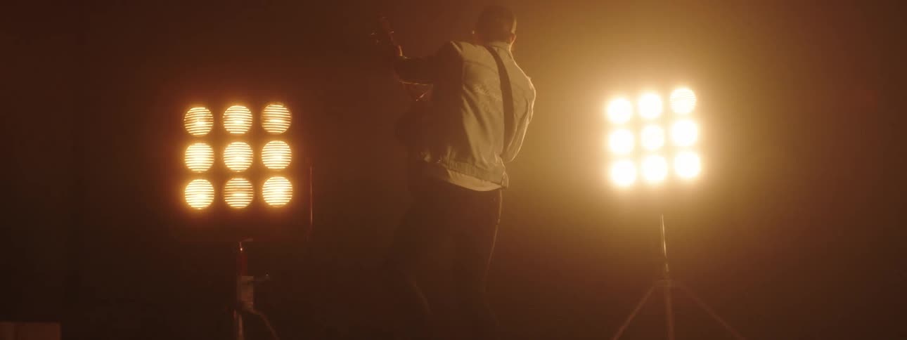 A guitarist plays the guitar before flashing stage lights on stage