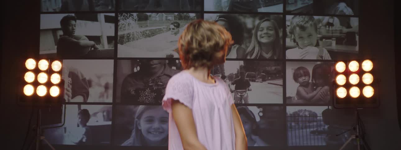A girl with her head turned looking back at a wall of videos