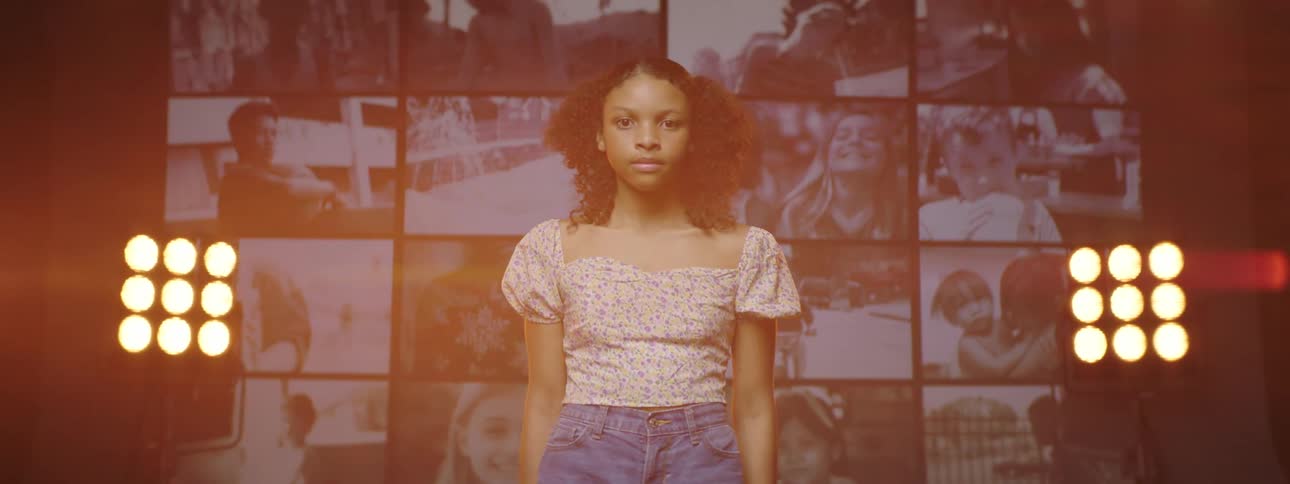 A young woman stands and poses in front of a wall of displays