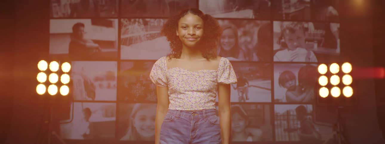 A portrait of a girl standing on a stage in front of a screen