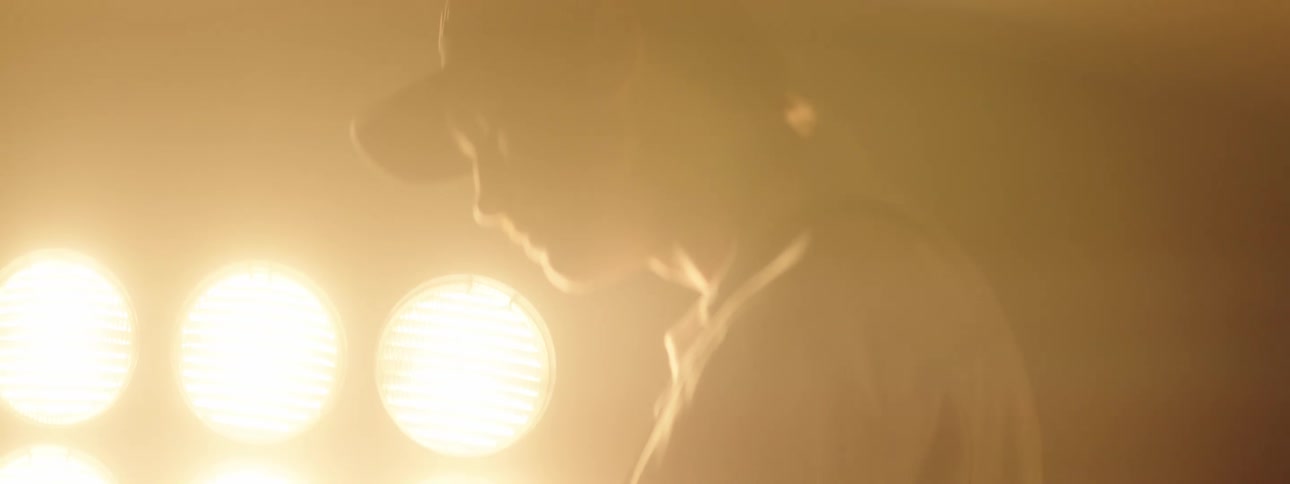 Guitarist stands near glaring stage lights playing guitar