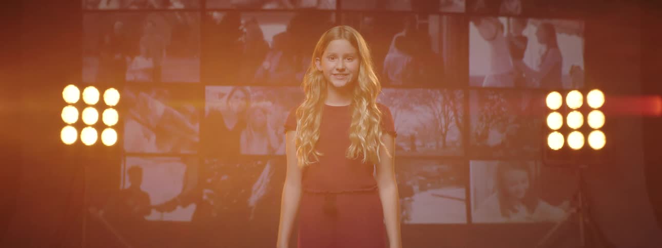 A girl that is standing on a stage with screens and lights