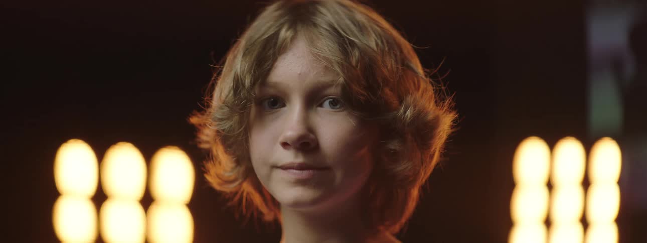 A child stands with stage lights glowing behind
