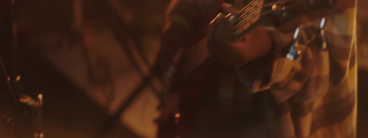 A guitarist plays the guitar under flashing lights on stage