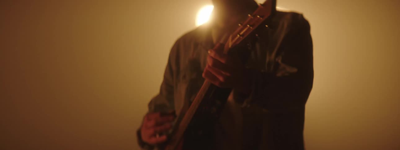 Musician playing acoustic guitar on stage in front of yellow flashing lights