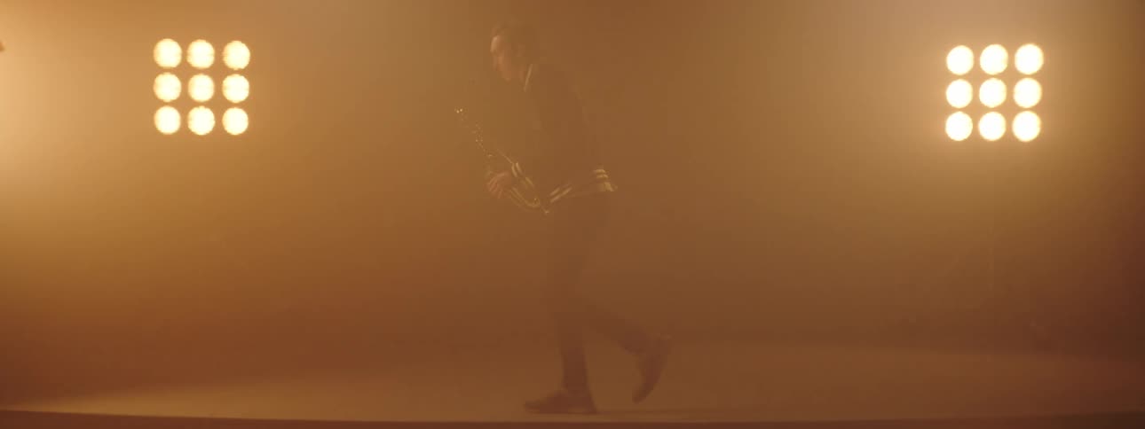 A man plays the saxophone and dances across the stage