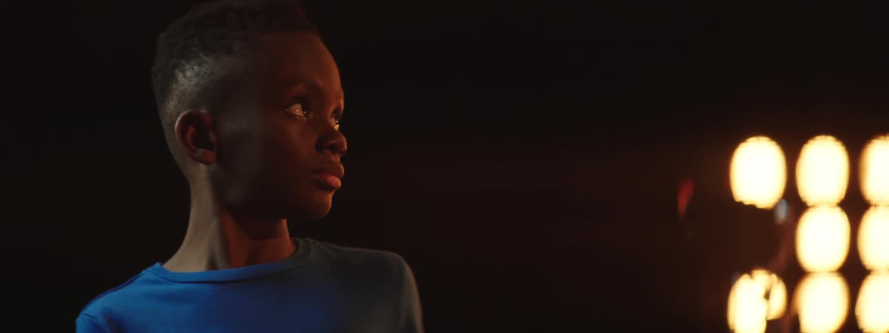 A boy on a stage with a spotlight and a wall in the background