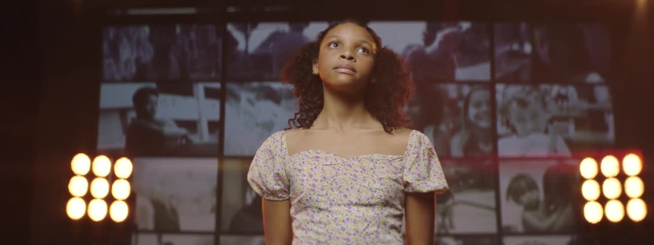 Young girl standing on stage in front of a giant digital display