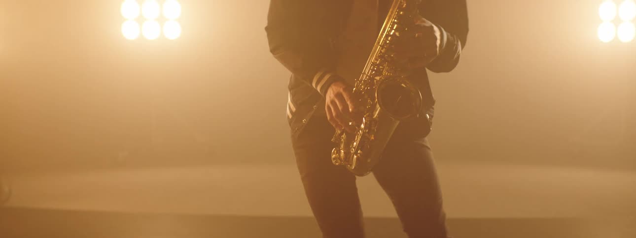 A saxophonist plays the saxophone and dances on stage