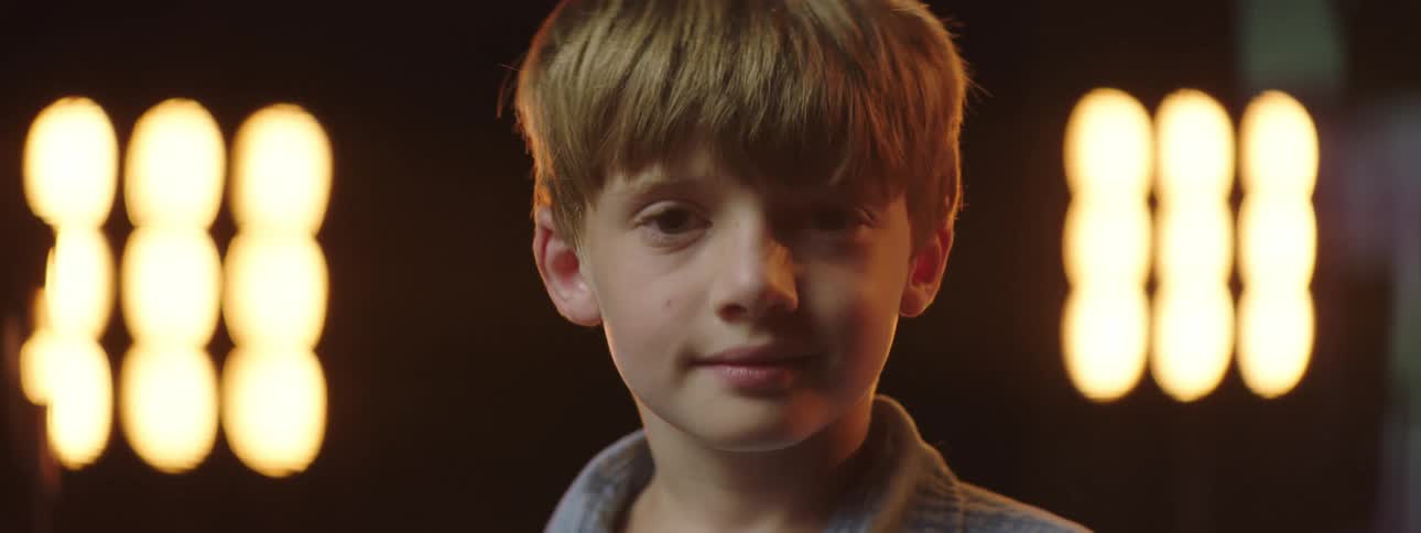 Blonde boy looks at the camera smiling on the stage