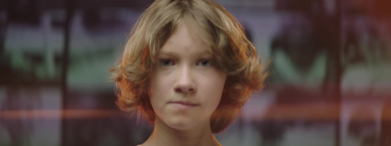 A child turns his head back from looking at the wall of videos playing behind him