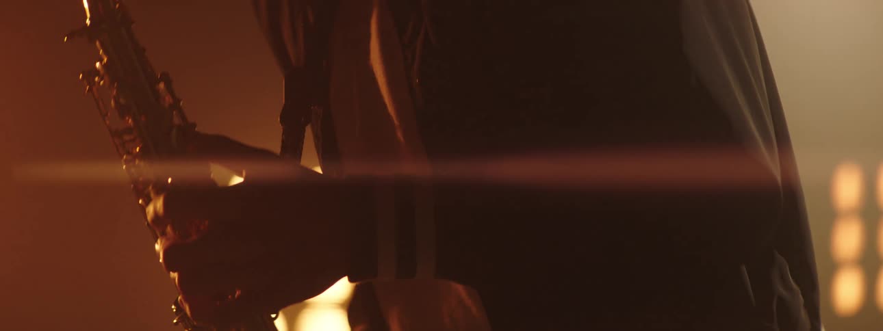 Young man playing the saxophone on a stage in front of yellow lights