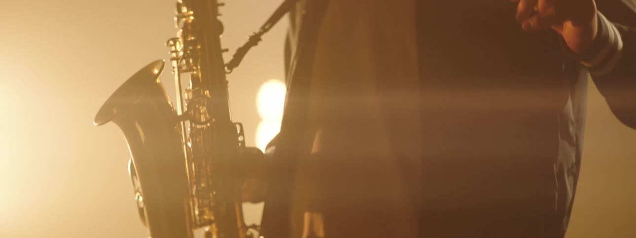 Musician plays saxophone on smoky stage under bright lights