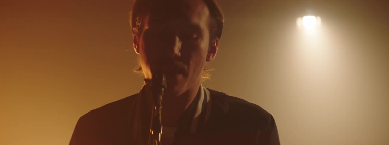 A man plays the saxophone in front of bright lights