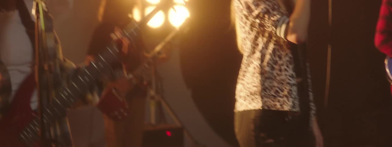 A woman sings while her band plays and stage lights shine and glare